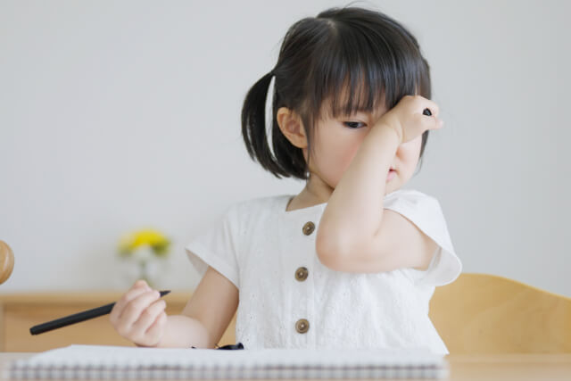 目をかく女の子